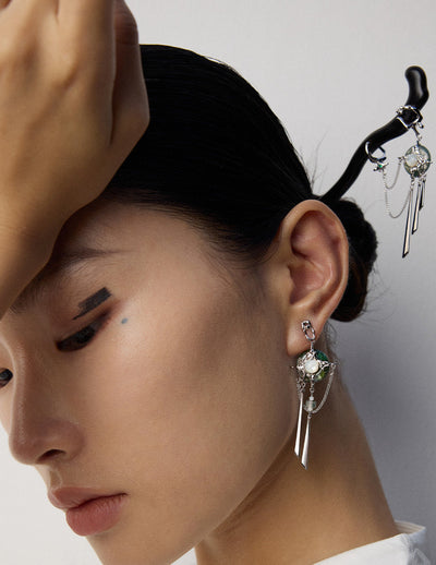 Close-up of a woman wearing an earring with a decorative hairpin on a plain background
